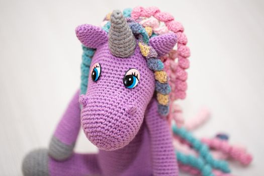 A knitted unicorn with a multicolored mane. A toy for a child.