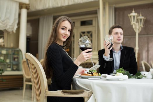 Beautiful woman and man in restaurant, holding glass of wine