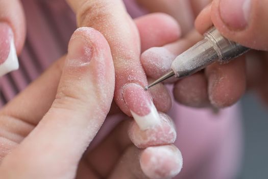 Closeup shot of master uses an electric machine to remove the nail polish during manicure in the salon. Hardware manicure. Concept of body care