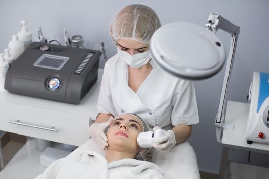 Cosmetology. Beautiful Woman Receiving Facial Skin Ultrasound Cavitation. Closeup Of Female Face Receiving Anti-Aging Cosmetics Using Ultrasound Cavitation Machine. Body Care