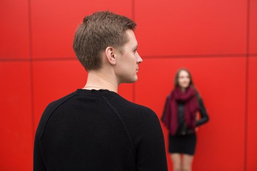 Young man and woman in passion, emotion, on the street with a backdrop of the red wall. Fashion