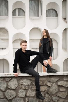 young sexy couple in black clothes posing with a background on the white wall