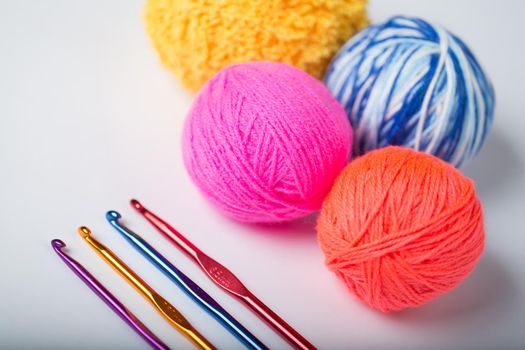 a group of multi-colored balls of yarn and knitting needles on a white background