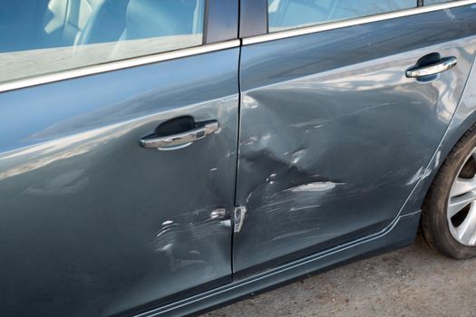 Sheet metal damage on a blue car after an accident