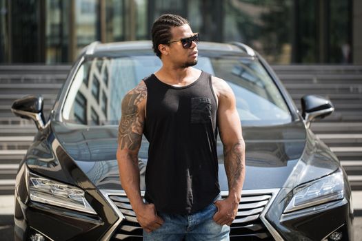 An African-American man poses near his car