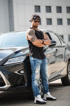 An African-American man poses near his car