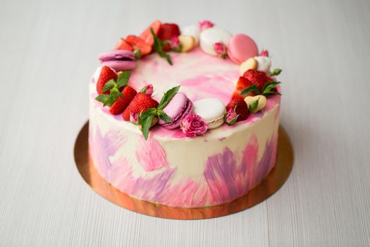Beautiful cake with strawberries and macaroons on a white table