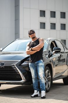 An African-American man poses near his car