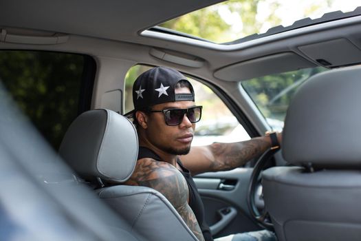 Stylish black man sitting behind the wheel of luxury car.