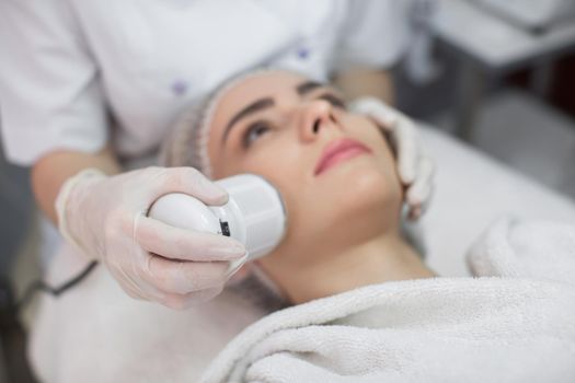 Cosmetology. Beautiful Woman Receiving Facial Skin Ultrasound Cavitation. Closeup Of Female Face Receiving Anti-Aging Cosmetics Using Ultrasound Cavitation Machine. Body Care