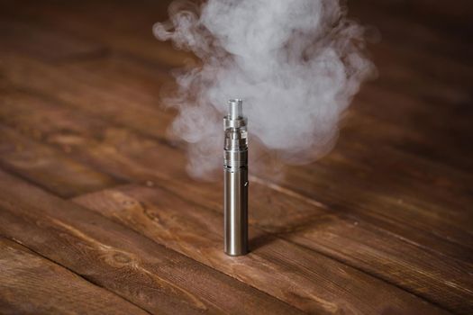 Electronic cigarette on a wooden table. Smoke.