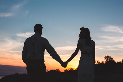 Loving couple together outdoor in mountains over scenic sunset sky background.