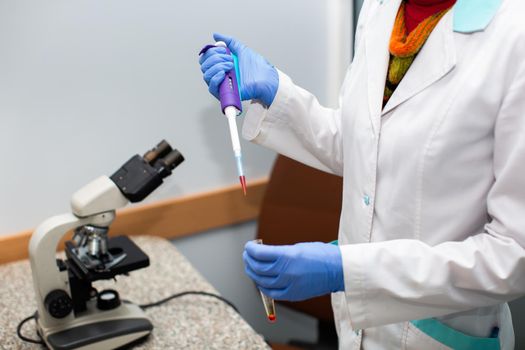 A scientist working with blood samples and a microscope in the laboratory