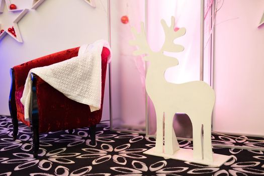 New Year's decor: a red armchair, a white plaid and a deer statue.
