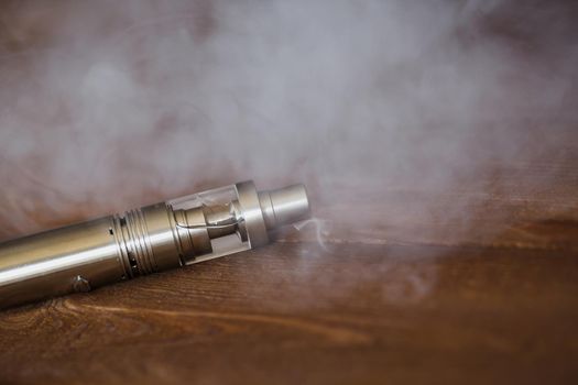 Electronic cigarette on a wooden table. Smoke.