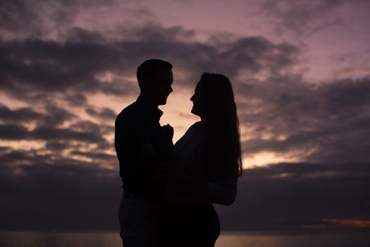 Silhouette of a young couple at sunset on the beach near the ocean