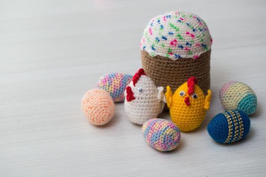 Knitted Easter eggs, chicken, cock on a white table