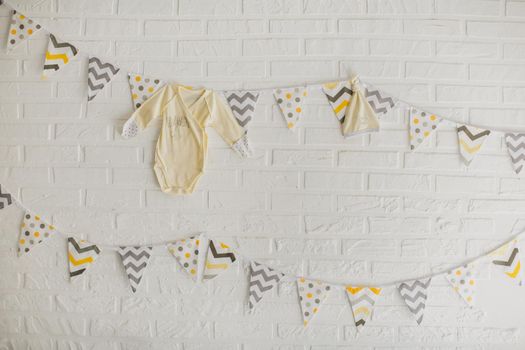 Flags and clothes of a baby hanging on a white stone wall in the Studio