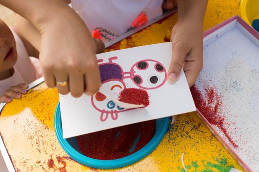 A child draws with colored sand picture. Cartoon characters.