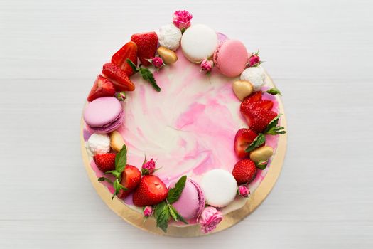 Beautiful cake with strawberries and macaroons on a white table