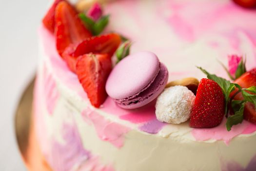 Beautiful cake with strawberries and macaroons on a white table