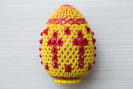 Egg decorated with small beads on a white table