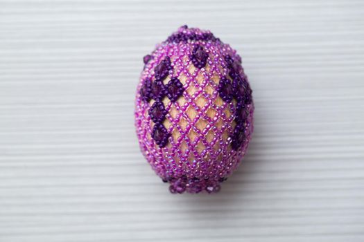 Egg decorated with small beads on a white table