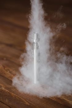 Electronic cigarette on a wooden table. Smoke.