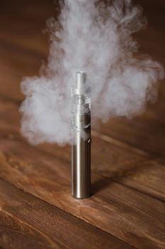 Electronic cigarette on a wooden table. Smoke.