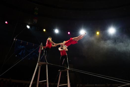 Bright performance of acrobats under the dome of the circus