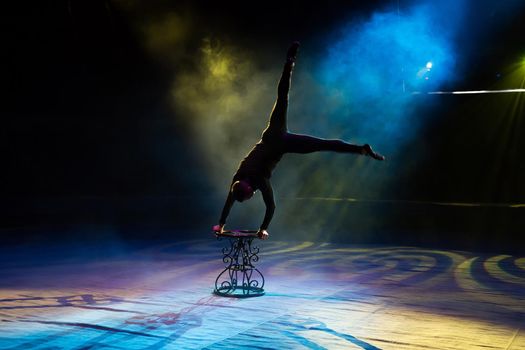 Acrobat performs a difficult trick in the circus.
