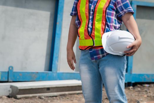 Asian woman civil construction engineer worker or architect with helmet and safety vest happy working at a building or construction site