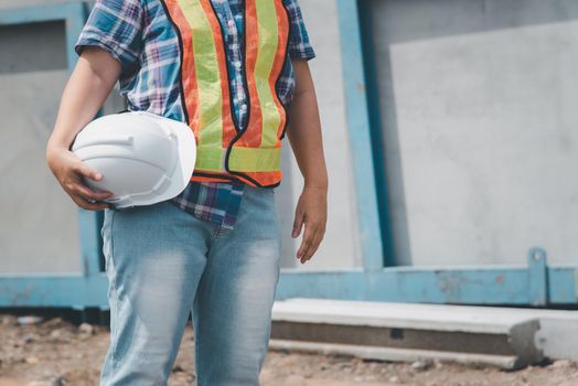 Asian woman civil construction engineer worker or architect with helmet and safety vest happy working at a building or construction site