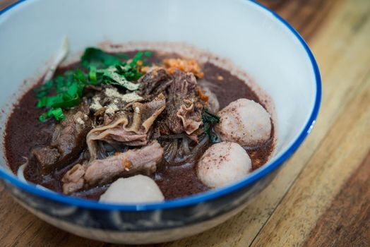 Braised beef clear noodle with meat balls soup stew (Ekaehla meat) with vegetable in bowl for sale at Thai street food market or restaurant in Thailand