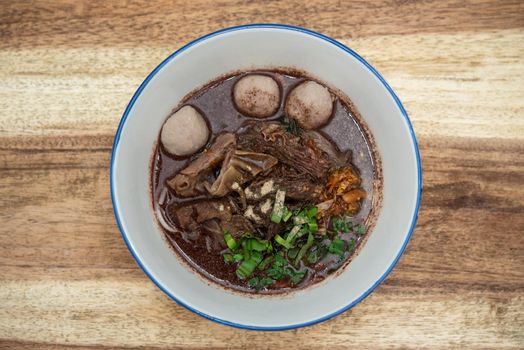 Braised beef clear noodle with meat balls soup stew (Ekaehla meat) with vegetable in bowl for sale at Thai street food market or restaurant in Thailand