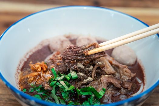 Braised beef clear noodle with meat balls soup stew (Ekaehla meat) with vegetable in bowl for sale at Thai street food market or restaurant in Thailand