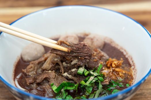 Braised beef clear noodle with meat balls soup stew (Ekaehla meat) with vegetable in bowl for sale at Thai street food market or restaurant in Thailand