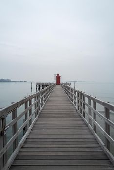 Small red old lighthouse at the end of a long jetty.