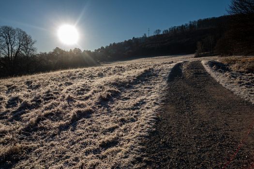 The sun is rising over a landscape marked by the morning frost.