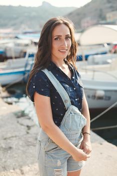 Portrait of a beautiful girl against a wooden pier and yachts