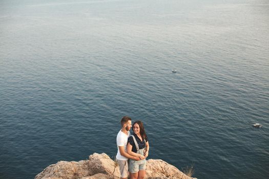 Guy and girl, on the edge of the cliff against the backdrop of mountains and ocean