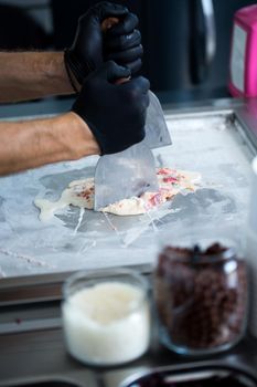 Stir-fried ice cream rolls at freeze pan. Rolled ice cream, hand made ice cream dessert. Fried ice cream machine with steel chilled pan.