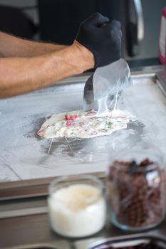 Stir-fried ice cream rolls at freeze pan. Rolled ice cream, hand made ice cream dessert. Fried ice cream machine with steel chilled pan.