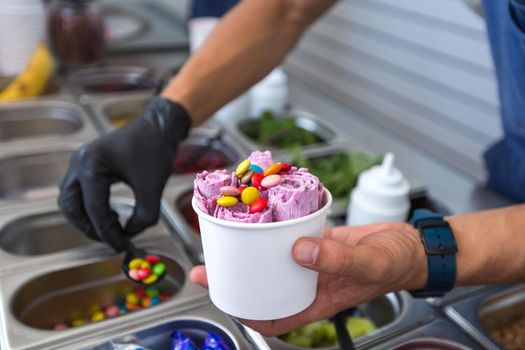 Stir-fried ice cream rolls at freeze pan. Rolled ice cream, hand made ice cream dessert. Fried ice cream machine with steel chilled pan.