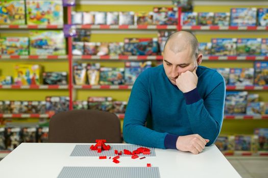 man plays a designer of colored plastic figures