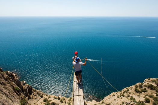 Rope jumping off a cliff with a rope in the water. The ocean. Sea. Mountain