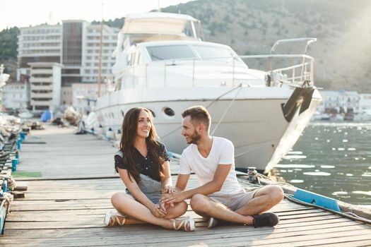 Guy and girl, are sitting on a wooden pier