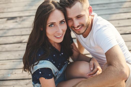Guy and girl, are sitting on a wooden pier