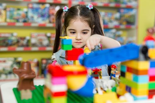 Little girl playing with building blocks in the store