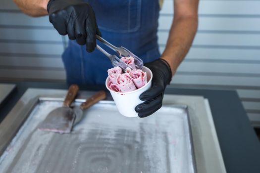 Stir-fried ice cream rolls at freeze pan. Rolled ice cream, hand made ice cream dessert. Fried ice cream machine with steel chilled pan.